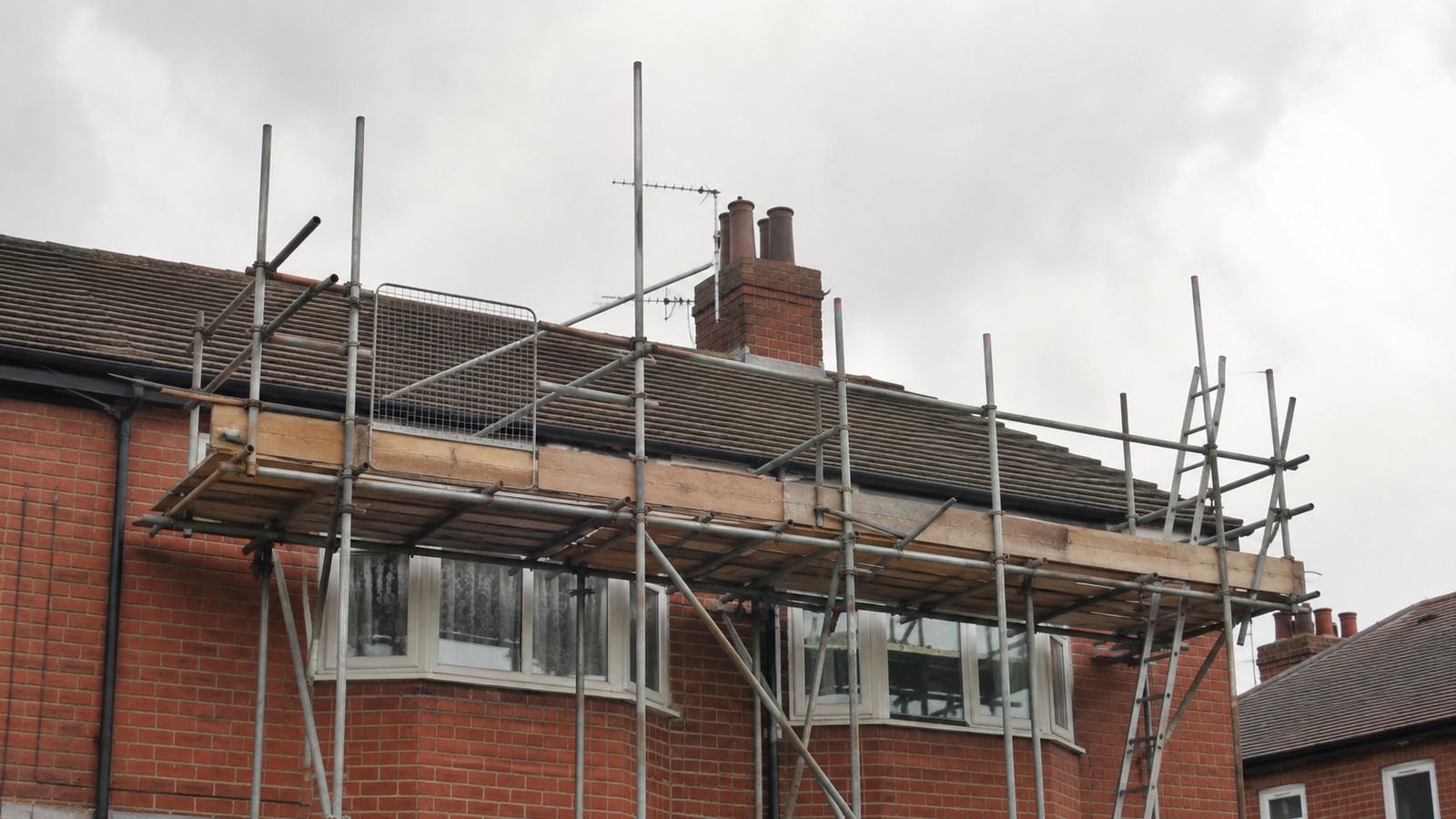 Brick house undergoing substantial building work with scaffolding